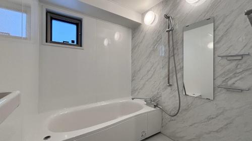 Baño blanco con bañera y espejo en 島の宿 Amanzaーアマンツァー, en Ishigaki Island