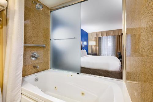 La salle de bains est pourvue d'une baignoire, d'un lit et d'un miroir. dans l'établissement Holiday Inn Express New York City Chelsea, an IHG Hotel, à New York