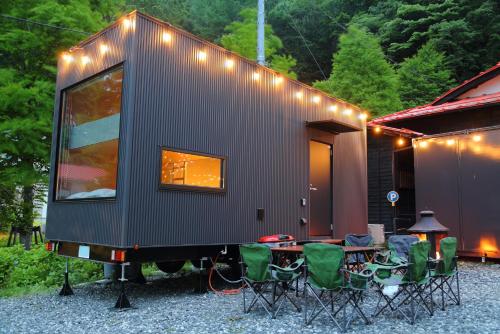 a tiny house with a group of chairs and a table at Fuji Time Traveler BBQが楽しめる 河口湖湖畔すぐそば 6名宿泊可のトレーラーハウス in Azagawa