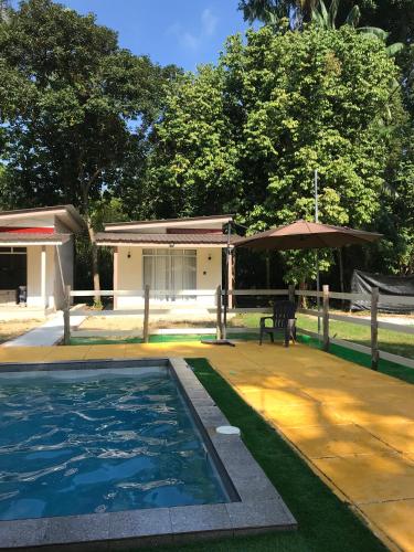 a swimming pool with a table and an umbrella at Rajawali Riverside Retreat in Dungun