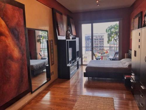 a living room with a television and a large window at Loft in Reforma 27 with Amazing balcony views on the 9th floor in Mexico City