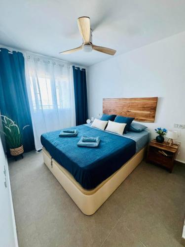 a bedroom with a bed with blue sheets and a fan at Encanto del Mar La manga, Sea View in San Blas