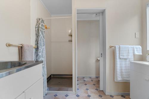 a bathroom with a shower and a sink and a mirror at Raglan Beach Retreat - Raglan Holiday Home in Raglan