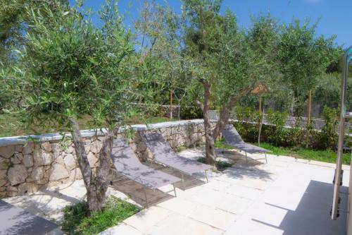a group of benches with trees next to a stone wall at Villa Buon Vento in Vignacastrisi