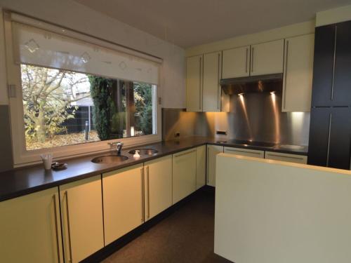 a kitchen with white cabinets and a sink and a window at Villa in Zottegem with Pool and Sauna in Wolvenhoek