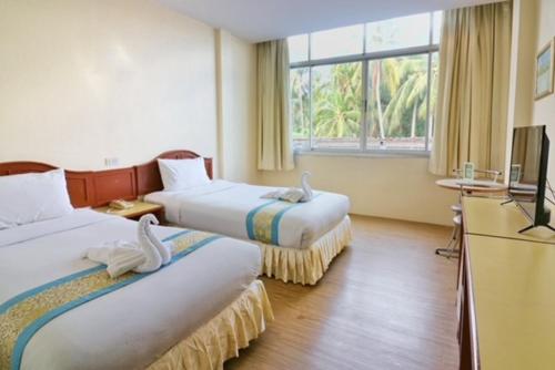 a hotel room with two beds and a television at Chumphon Gardens Hotel in Chumphon