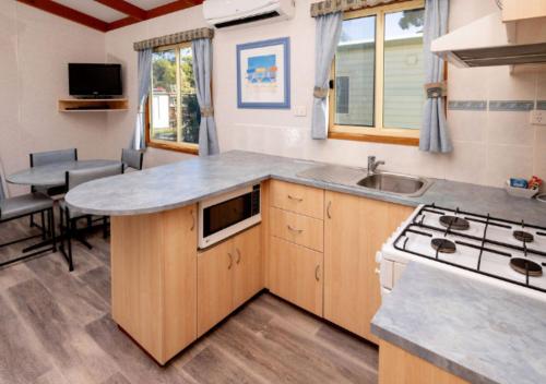 a small kitchen with a sink and a stove at Echo Holiday Parks - Normanville in Normanville