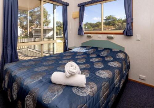 a bedroom with a bed with a towel on a pillow at Echo Holiday Parks - Normanville in Normanville