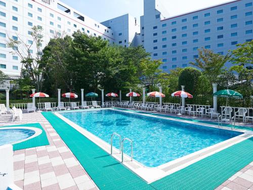una gran piscina con sombrillas y sillas en Hotel Nikko Narita en Narita