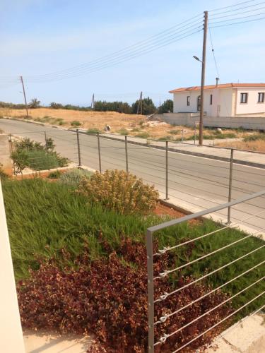 an empty street with a fence and a road at Galatia's House in Kouklia