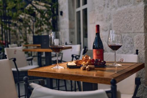 a table with two wine glasses and a bottle of wine at Arbiana Heritage Hotel in Rab