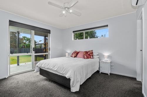 ワイプにあるFamily Haven - Waipu Holiday Homeのベッドと窓のある白い寝室