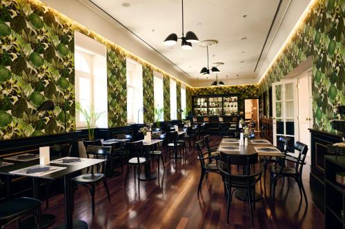 a restaurant with tables and chairs and plants on the walls at Arbiana Heritage Hotel in Rab
