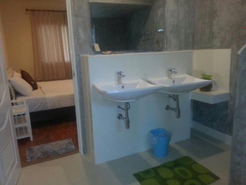 ein Badezimmer mit 2 Waschbecken und ein Schlafzimmer mit einem Bett in der Unterkunft Khanom Garden Suite in Khanom