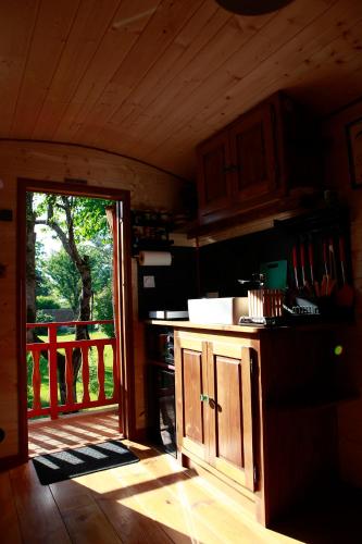 une cuisine avec une porte s'ouvrant sur une terrasse couverte dans l'établissement La Chouette Roulotte, à Fresnay
