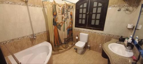 a bathroom with a tub and a toilet and a sink at Nile Dream Apartments in Luxor
