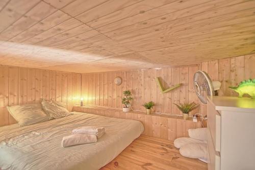 une chambre avec un lit avec un plafond en bois dans l'établissement La cabane des oiseaux, à Hyères