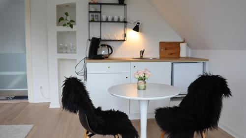 a white table with black tails and two chairs at Møllehusets lejligheder i Ikast tæt ved Herning, Silkeborg og Århus in Ikast