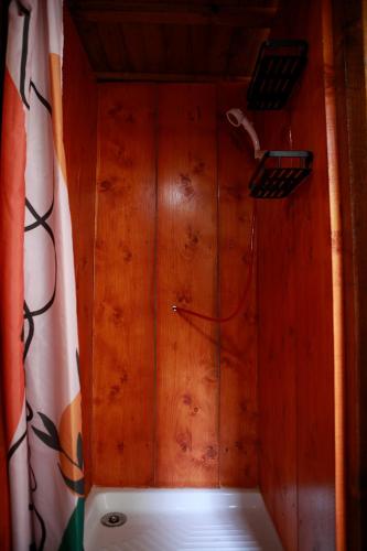 une chambre avec un mur lambrissé de bois et une douche dans l'établissement La Chouette Roulotte, à Fresnay