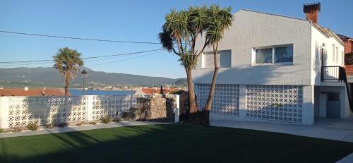 a white house with a fence and palm trees at La de Simón in A Guarda
