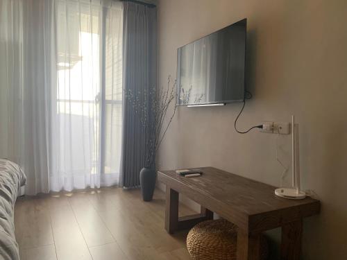 a room with a table and a tv on the wall at 谷園酒店公寓Good Garden Apartment in Taichung