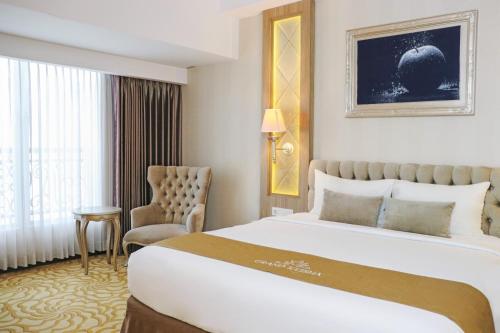 a hotel room with a large bed and a chair at Grand Keisha Yogyakarta in Yogyakarta
