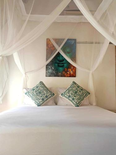 a bedroom with a bed with a painting on the wall at Bintang Tiga Bungalows Gili Air in Gili Air