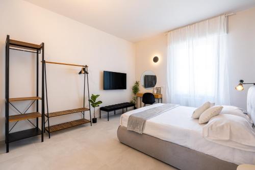 a white bedroom with a bed and a television at Osmann Space in La Spezia