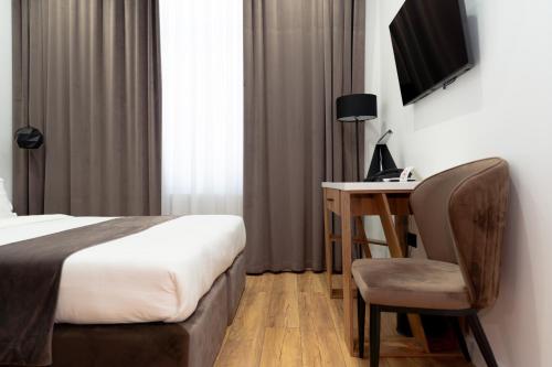 a bedroom with a bed and a desk with a chair at Harmony Luxury Hotel Tashkent in Tashkent