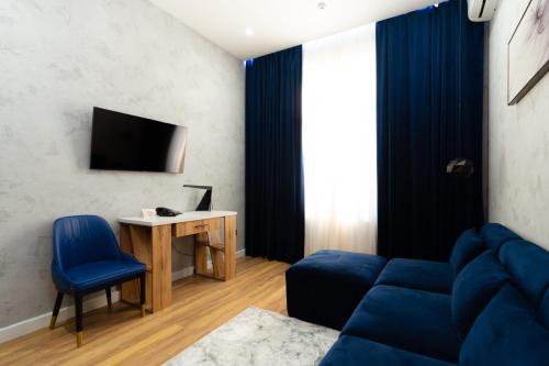 a living room with a blue couch and a desk at Harmony Luxury Hotel Tashkent in Tashkent