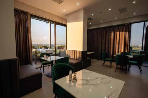 a restaurant with tables and chairs and large windows at Harmony Luxury Hotel Tashkent in Tashkent
