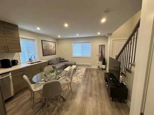 a living room with a glass table and a kitchen at Bright and cozy modern home in Vancouver - central to YVR-Downtown - Free Private Parking in Vancouver