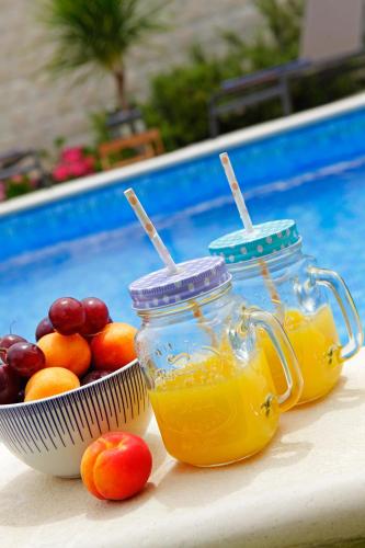two mason jars and a bowl of fruit next to a pool at Villa Sania in Bol