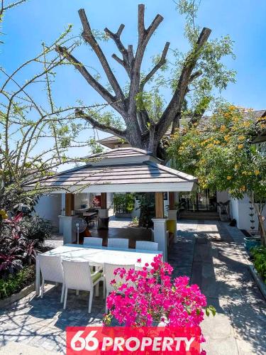a table with an umbrella and some pink flowers at Phuk Phirom Twin Villas in Chiang Mai