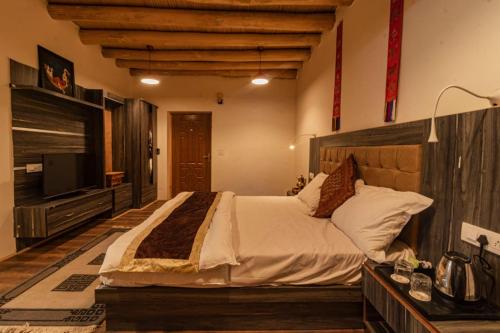 a bedroom with a large bed and a flat screen tv at Hotel Sindhu in Leh
