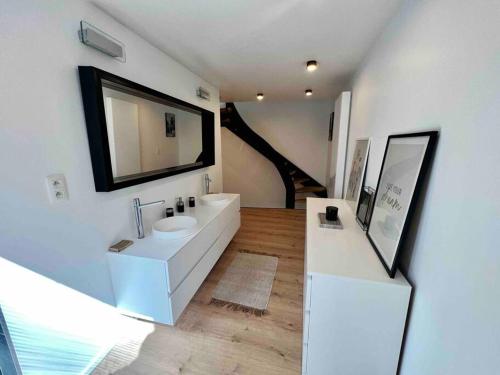 Un baño blanco con lavabo y espejo. en Triplex d'architecte en hypercentre, en Lieja