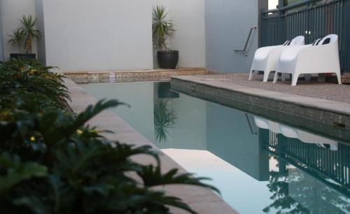 a group of white chairs sitting next to a swimming pool at Lennox Holiday Apartments in Lennox Head