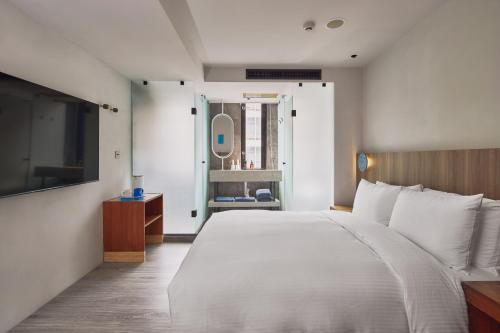 a bedroom with a large white bed and a mirror at The Blue by Just Inn in Taipei