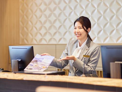 a woman sitting in front of a desk at The Kanazawa Sainoniwa Hotel in Kanazawa
