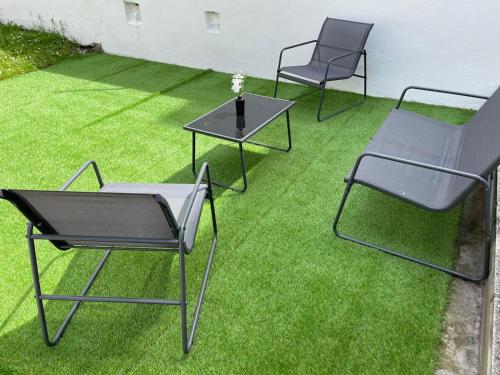 three chairs and a table on a lawn at Le rafale Proche aeroport et Parc Exposition in Le Bourget