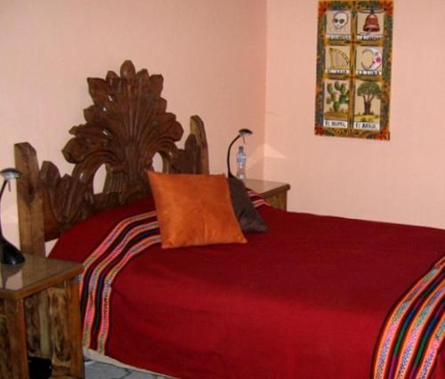 a bedroom with a red bed with a wooden headboard at El Zopilote Mojado in Guanajuato