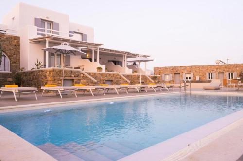 a pool in front of a house with tables and chairs at Sea Wind Villas and Suites in Tourlos