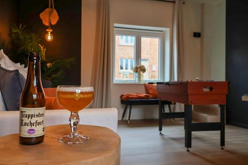 una botella de cerveza sentada en una mesa con un vaso en Le Nid de la Trappiste - MAISON avec JARDIN et BARBECUE, en Rochefort