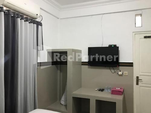 a bathroom with a toilet and a television on a wall at Hotel Gamary RedPartner Sidorejo in Pasuruan