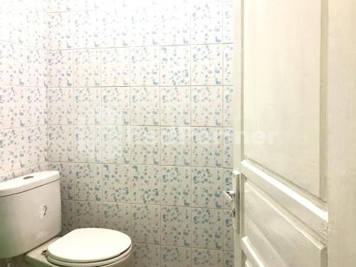 a bathroom with a toilet and blue and white tiles at Hotel Gamary RedPartner Sidorejo in Pasuruan