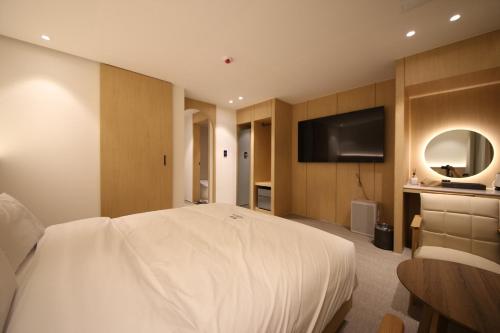 a bedroom with a white bed and a flat screen tv at H avenue Hotel Jeonju Deokjin in Jeonju