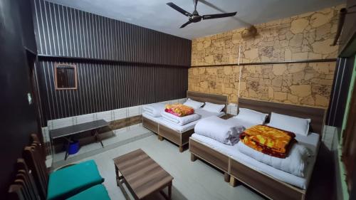 a room with two beds and a couch and a table at J M S Guest House in Joshīmath
