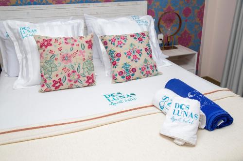 a bed with four pillows and a towel on it at Dos Lunas Aparthotel in J. E. Estigarribia