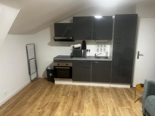 a kitchen with black cabinets and a wooden floor at Studio 30m2 Hyper centre in Ajaccio