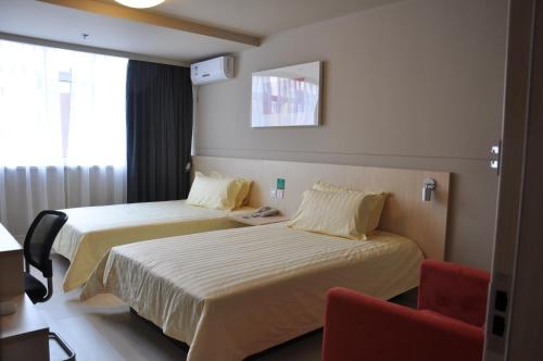 a hotel room with two beds and a red chair at Jinjiang Inn Shenyang International Exhibition Center Sujiatun Railway Station in Shenyang